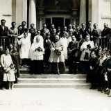 Per Goccia di Latte in quarant'anni di attivit� non mancarono onorificenze, premi e medaglie. Ecco una foto di una cerimonia tenutasi nel 1932, in occasione della visita all�ente dell�arcivescovo Augusto Curi. Si vedono volontari e sostenitori della Goccia posare sulle sue scalinate: Ave � in abito nero (e con il suo immancabile cappello con veletta) al centro tra il religioso e un altro parroco